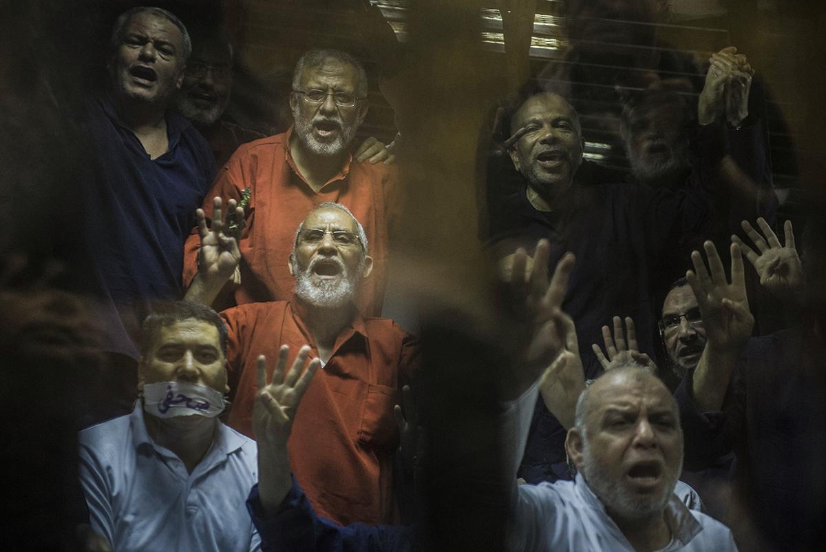 Vangitut Egyptin Muslimiveljeskunnan johtohenkilöt, keskellä ylin neuvonantaja Muhammed Badie, näyttävät Rabaa-käsimerkkiä protestoidakseen vuoden 2013 verilöylyä Rabaa el-Adaweja -aukiolla Kairossa. Kuva: Khaled Desouki / Getty Images