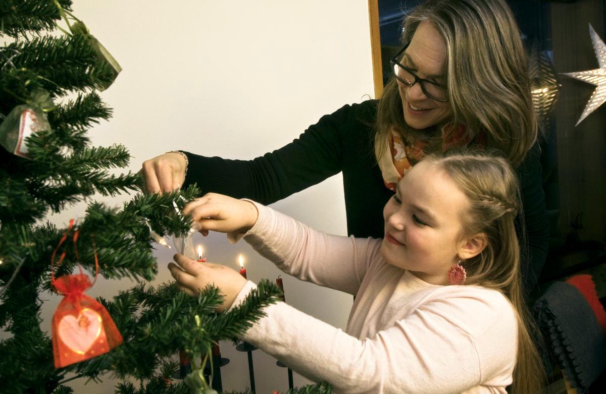 Sara ja Frida Nummi poimivat joulupuusta itselleen tuntemattomaksi jäävän lapsen lahjatoiveen. Kuva: Marianna Siitonen