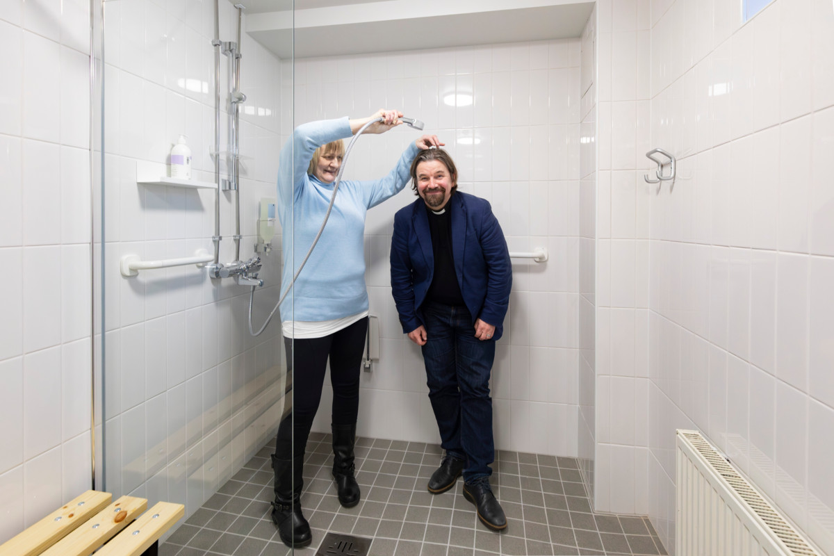 ”Tämä yhteisö on parantanut minut niin, että pystyn tekemään tätä työtä”, sanoo Annukka, joka huolehtii vapaaehtoisena esimerkiksi suihkutilojen siivouksesta. Varustamon avajaisissa Annukka poseerasi Paavalin seurakunnan kirkkoherran Kari Kanalan kanssa.