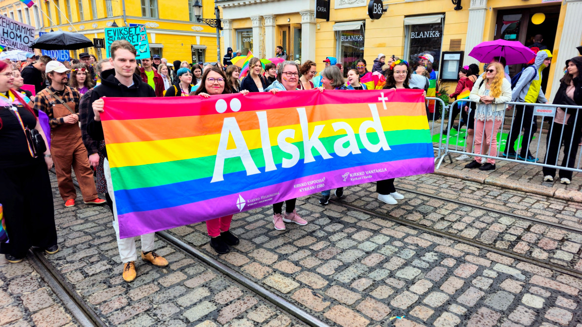 Pääkaupunkiseudun seurakuntien työntekijöitä ja vapaaehtoisia osallistui yhdessä vuoden 2025 Pride-kulkueeseen banderollien kera. Kuva: Eija Harju