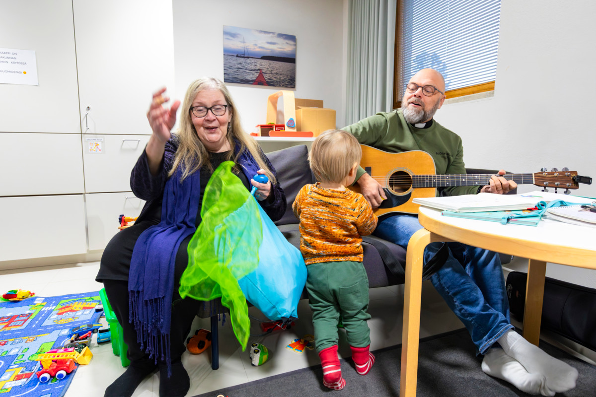 ”Olen itse yksinhuoltajataustainen äiti ja kävin täällä kerhossa ensiksi oman poikani kanssa. Ihastuin siihen, miten tervetulleita olimme tänne”, kertoo lastenohjaaja Eija Härkänen. Lauttasaaren seurakunnan pappi Markus Ek käy pitämässä kerhon musiikkituokioita.