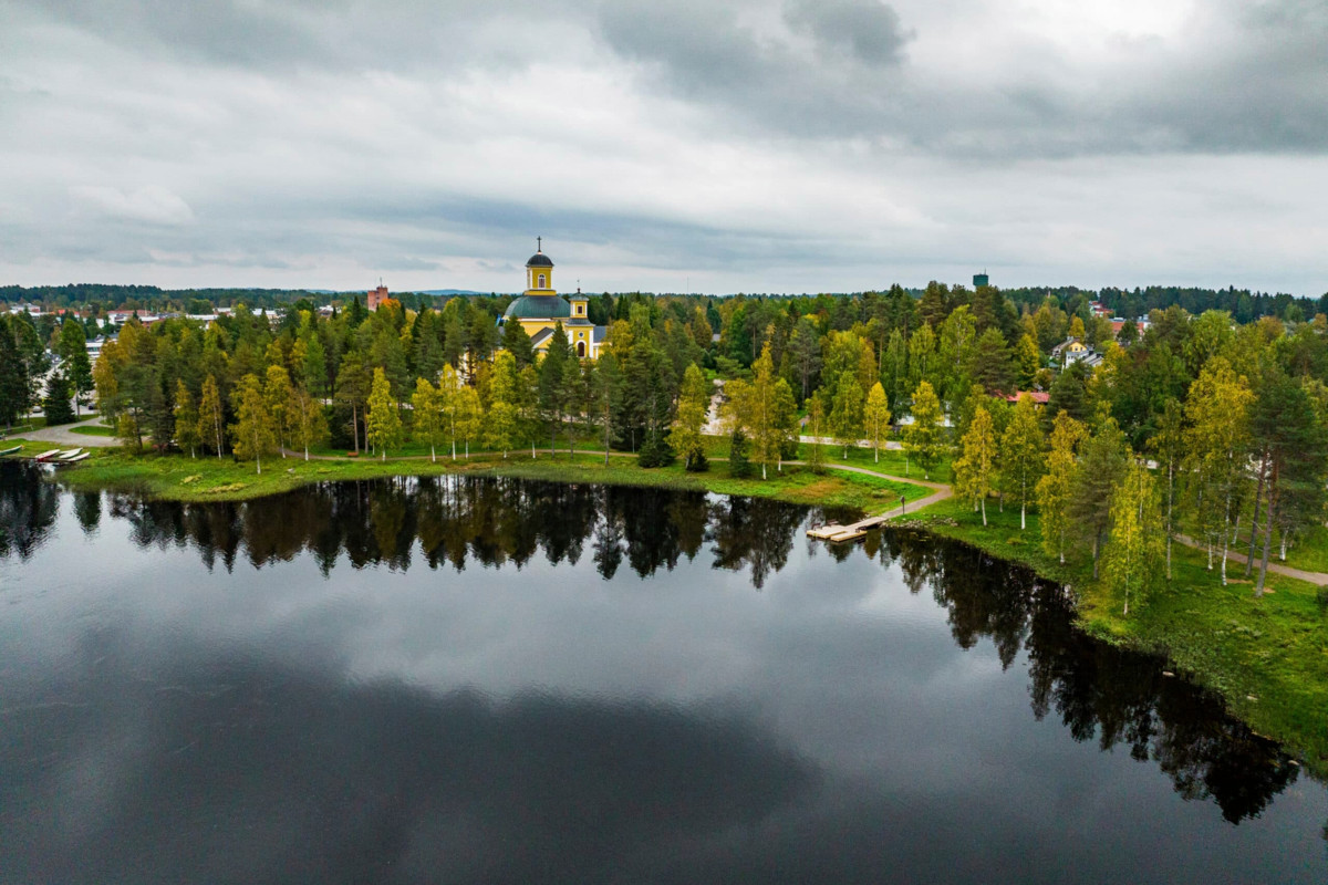 Uusklassinen ristikirkko sijaitsee Pajakkajoen rannassa. Kuva: Kuhmon matkailu
