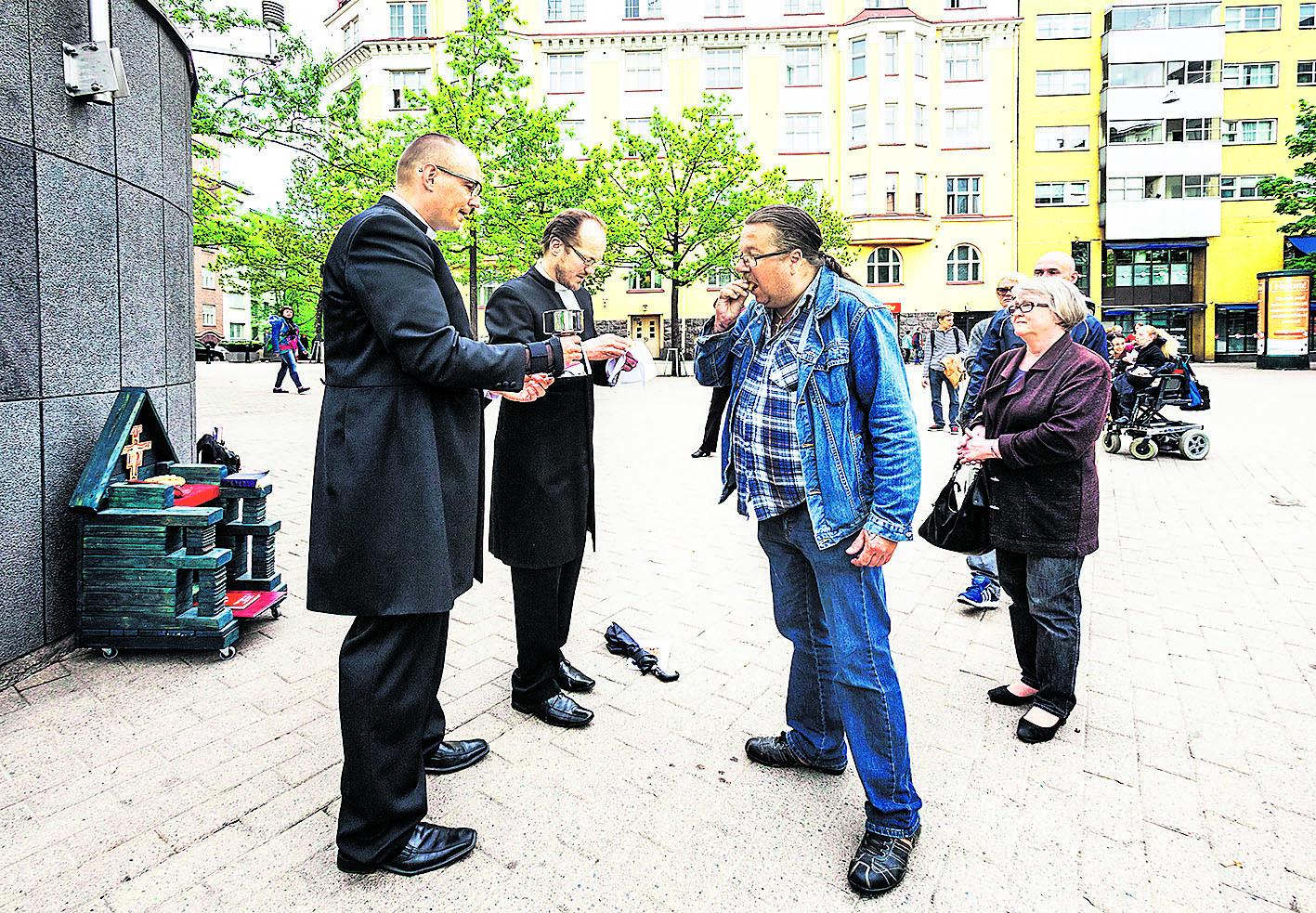 Katumessu Sörnäisissä. Jari Lyijynen sai ehtoollisen Ilkka Sariolan (vas.) ja Kai Sadinmaan jakamana.
