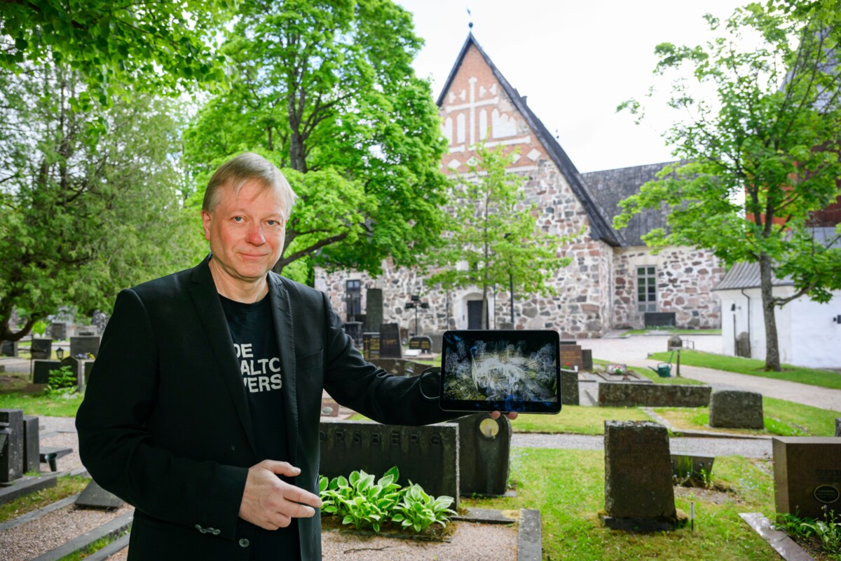 Hannu Hyyppä esittelee kuvaa Espoon tuomiokirkon 3D-mallinnoksesta. Hänet kuvattiin Tuomiokirkon edustalla. Kuva: Jussi Helttunen