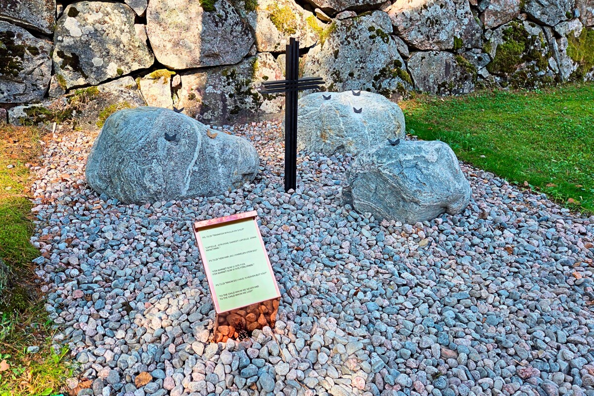 Ruskeasannalla muistelupaikan vieressä on kivimuuri, jonka harmaat kivet toistuvat muistelupaikan kivissä. Kivet symboloivat ikuisuutta ja turvaa, risti ylösnousemusta. Perhosta symboloivat täydellisyyttä.
