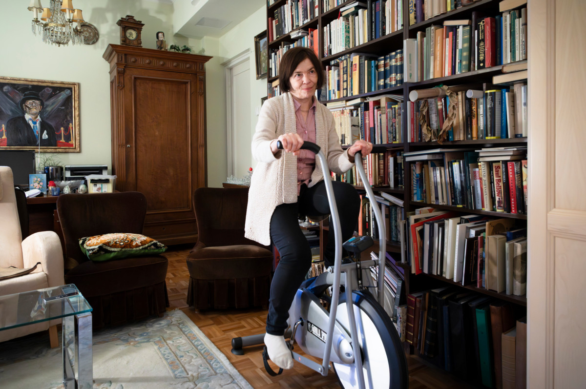 Marit Olander hoitaa kuntoaan samalla kun puoliso katselee vieressä televisiota. 