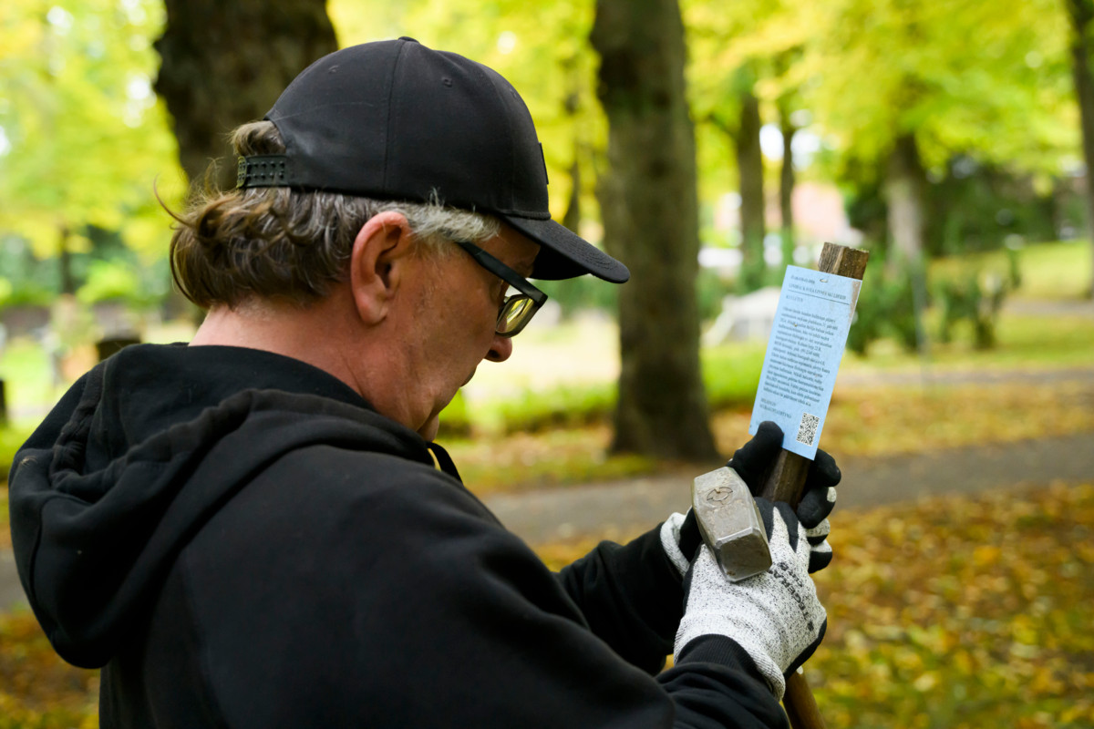 Malmin hautausmaan ammattityöntekijä Jan Backman lukee haudalta löytynyttä vanhempaa kuulutuskylttiä.