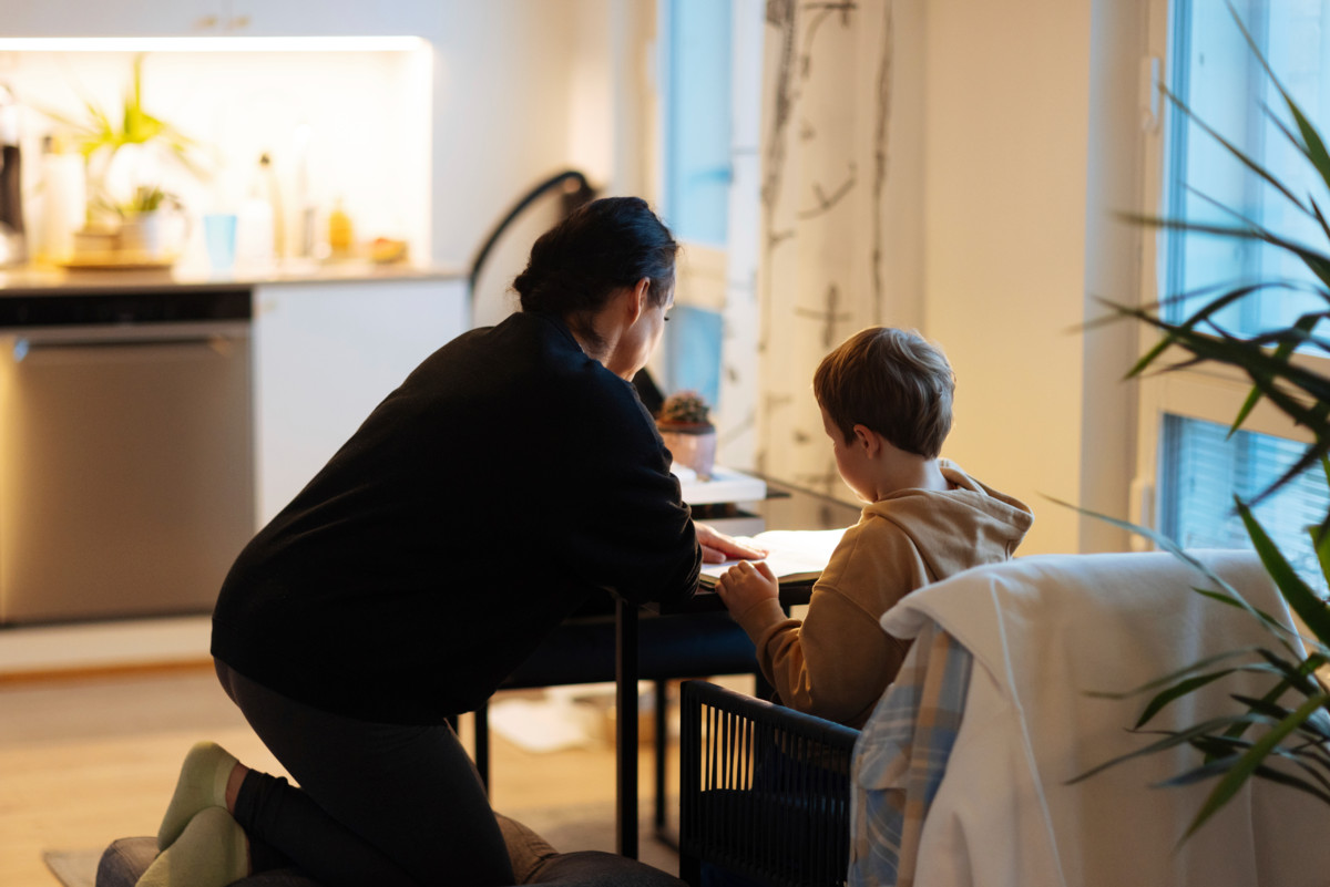 Kristi auttaa ekaluokkalaistaan läksyissä. Pöydän ääreen ei mahdu kahta vierekkäin.