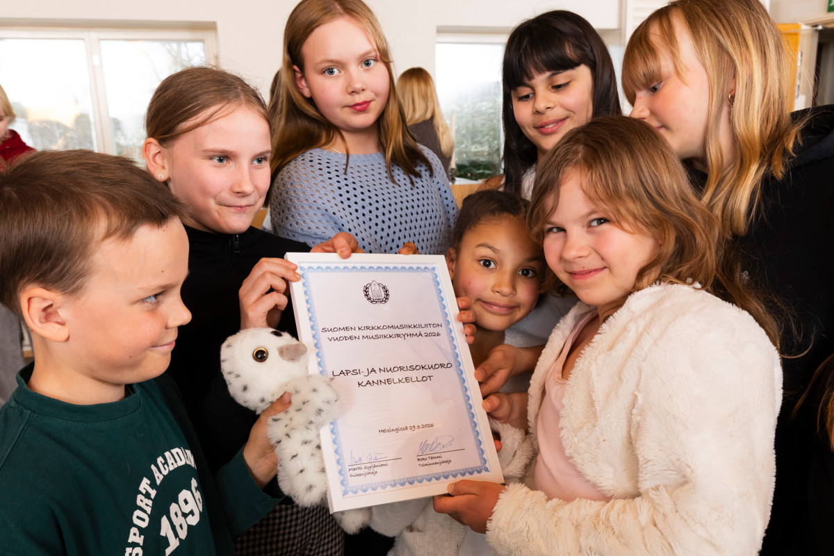 Lapsi- ja nuorisokuoro Kannelkellojen laulajat esittelevät kunniakirjaa, jonka kuoro sai Suomen Kirkkomusiikkiliitolta tänä keväänä.