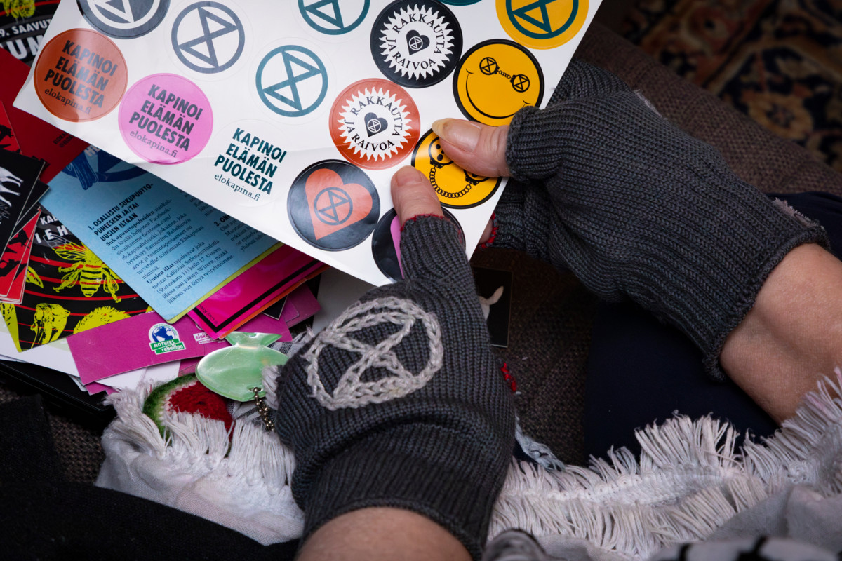 Elokapinan logolla varustetut kynsikkäät sekä tarroja ja esitteitä.