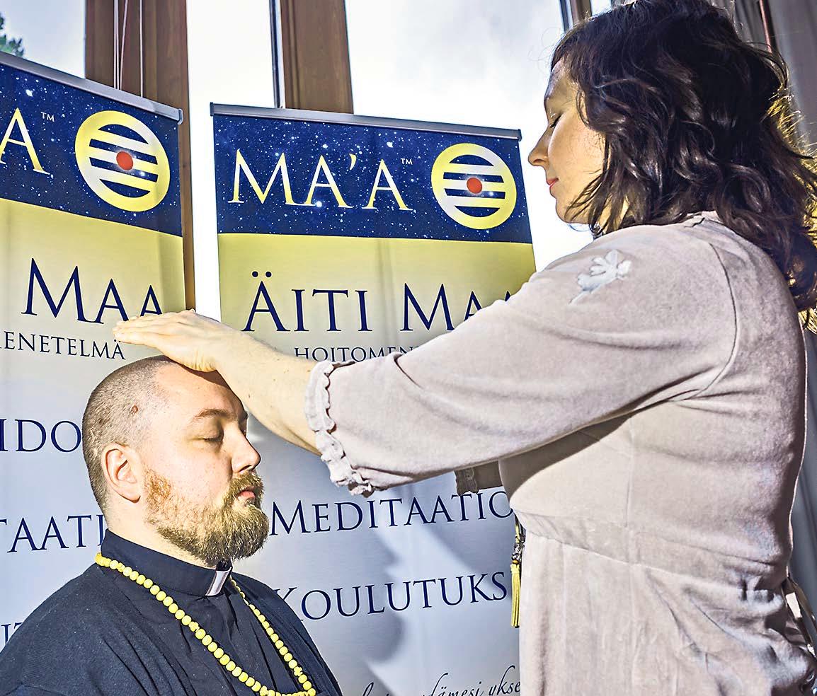 Pastori Henri Järvinen saa Äiti Maa -energiahoidon Kaisa Kivekkäältä.