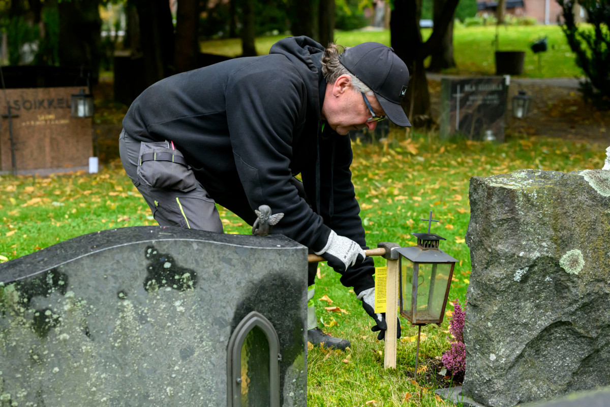 Malmin hautausmaan ammattityöntekijä Jan Backman asettaa kuulutuskyltin haudalle. 