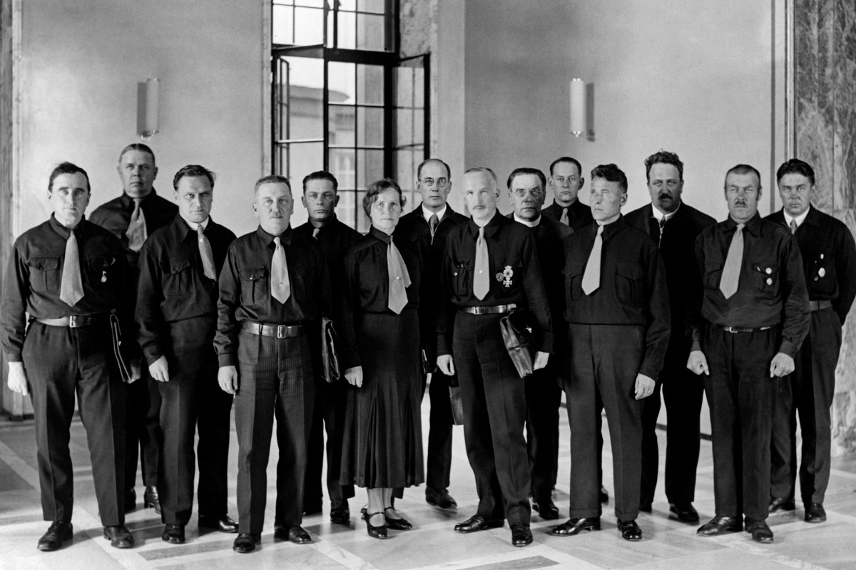 IKL:n ensimmäiset kansanedustajat ryhmäkuvassa 1933. Muiden pukeutuessa sinimustaan K.R. Kares (kuudes oikealta) ei luopunut papinpaidastaan. Hän oli ainut eduskuntaryhmästä, joka ei edes aluksi käyttänyt mustaa paitaa ja sinistä solmiota. IKL:n järjestöpukua ei kuvassa ole myöskään kahdella muulla pappisedustajalla eli L. P. Tapanaisella (kahdeksas) oikealta ja Yrjö Kivenojalla (kolmas oikealta). Pappeja oli ryhmässä alkuun neljä ja kauden lopussa kuusi. Kuva: Journalistinen kuva-arkisto/Otava/Museovirasto