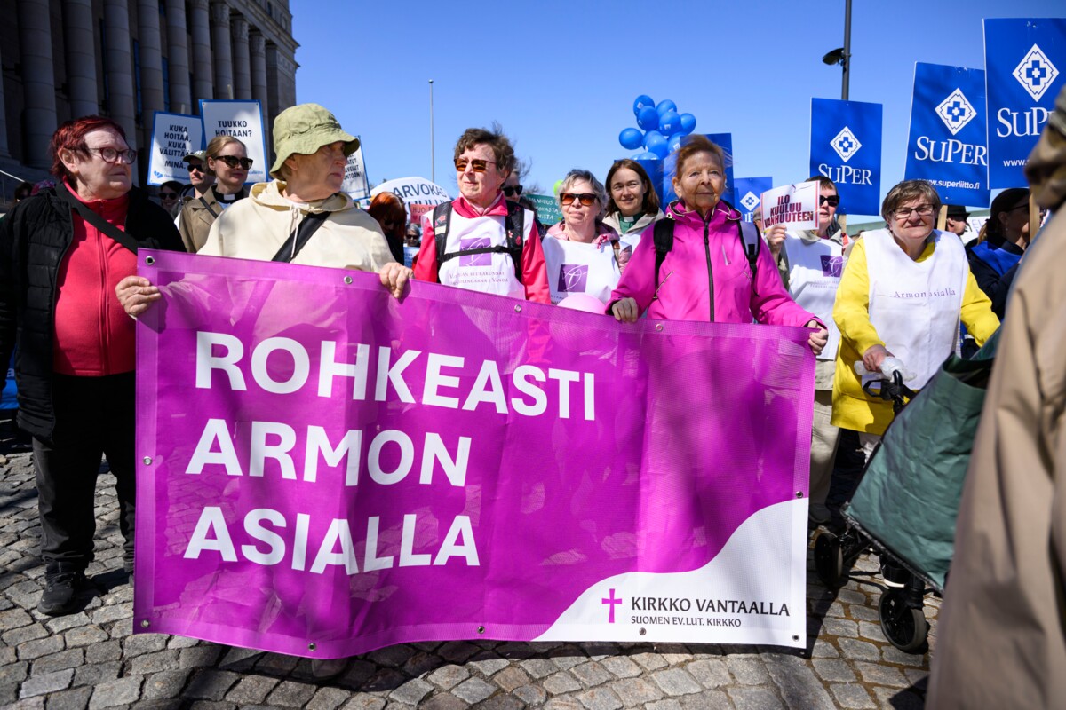 Vantaan seurakuntien porukka lähti liikkeelle eduskuntatalolta rollaattorimarssille. Kylttiä pitelevät Kaisa Mäntylä (vas.), Anneli Koskinen sekä Erja Ikonen. 