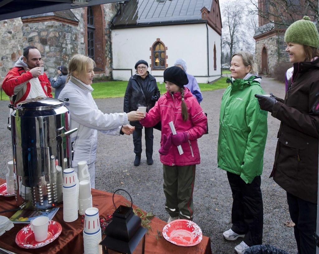 Tikkurilan seurakunnan vapaaehtoinen Pia Vallenius (vas.) oli jakamassa mehua Vantaan Pyhän Laurin kirkolla, mehujonossa Amalia Rantzou. Kuva: Markku Mattila.