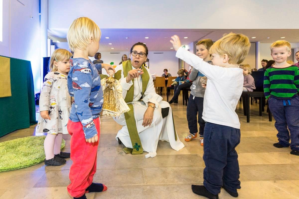 Kirsi Muurimäki saarnaa muskarimessussa lasten tasolla. Espoon tuomiokirkkoseurakunnan muskarimessu on hänen ja muskariopettajien yhdessä kehittämä musiikillinen lastenmessu.