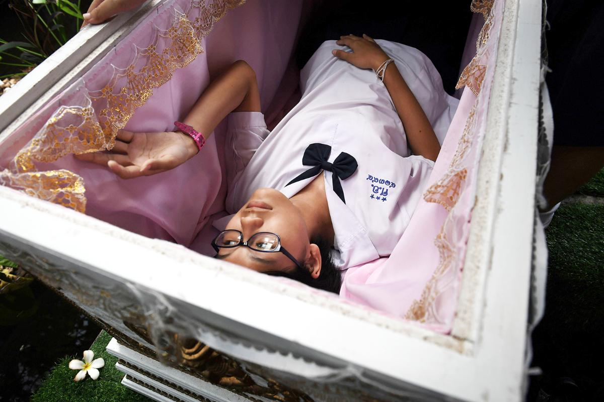 Thaimaalainen teini testaa arkkua Kid Mai Death Awarness -kahvilassa Bangokissa. Kyseessä on yhdistetty lounaskahvila ja näyttelytila, jonka tarkoituksena on jakaa tietoa buddhalaisuuden suhteesta kuolemaan.