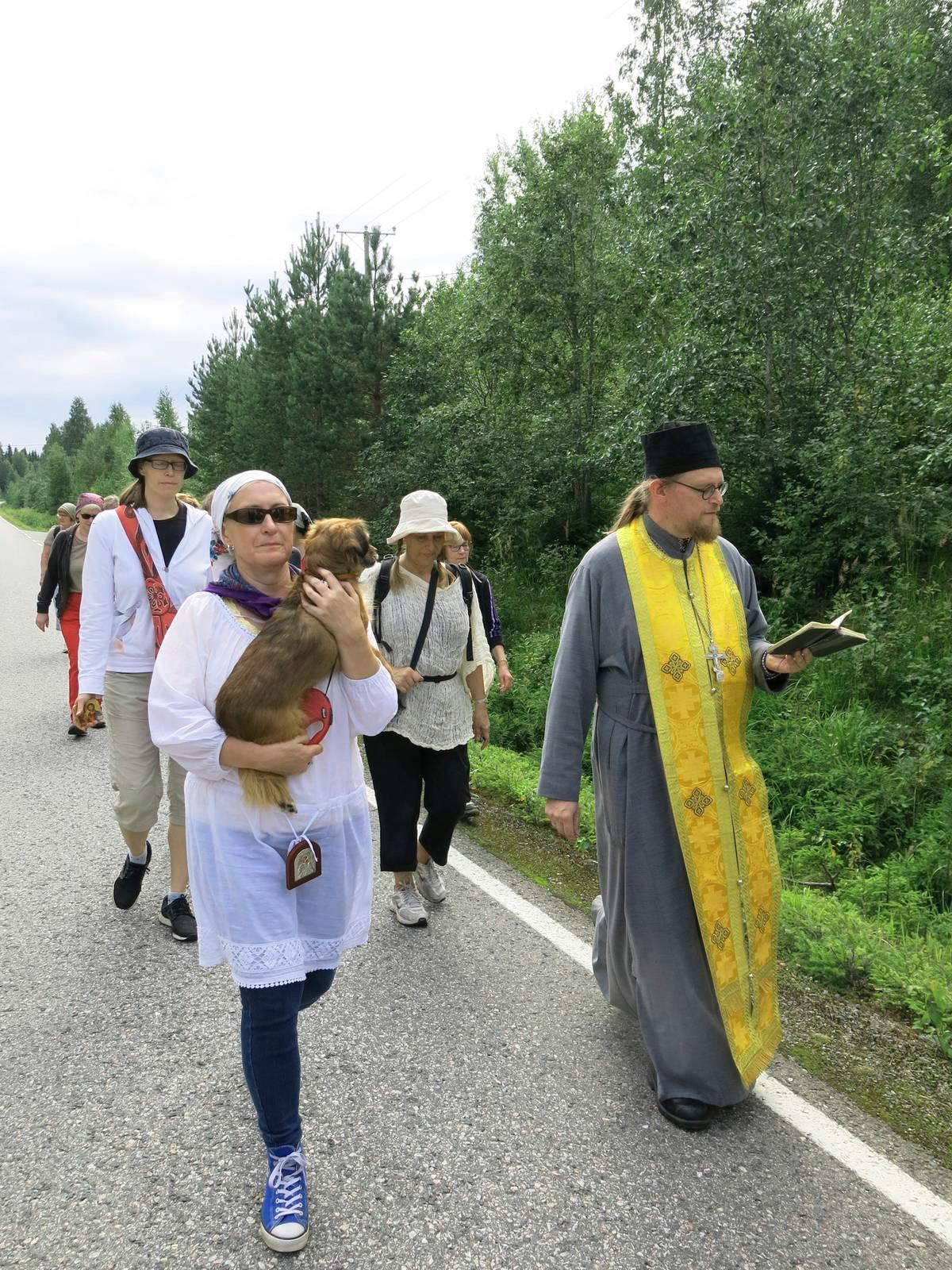 – Ristisaatto on osa Karjalan ortodoksien etnistä identiteettiä, Auli Leskinen arvioi. Tässä hän on Luna-koiransa kanssa Saarivaaran ristisaatossa. Vieressä kulkee ortodoksi-isä Tuomas Järvelin.