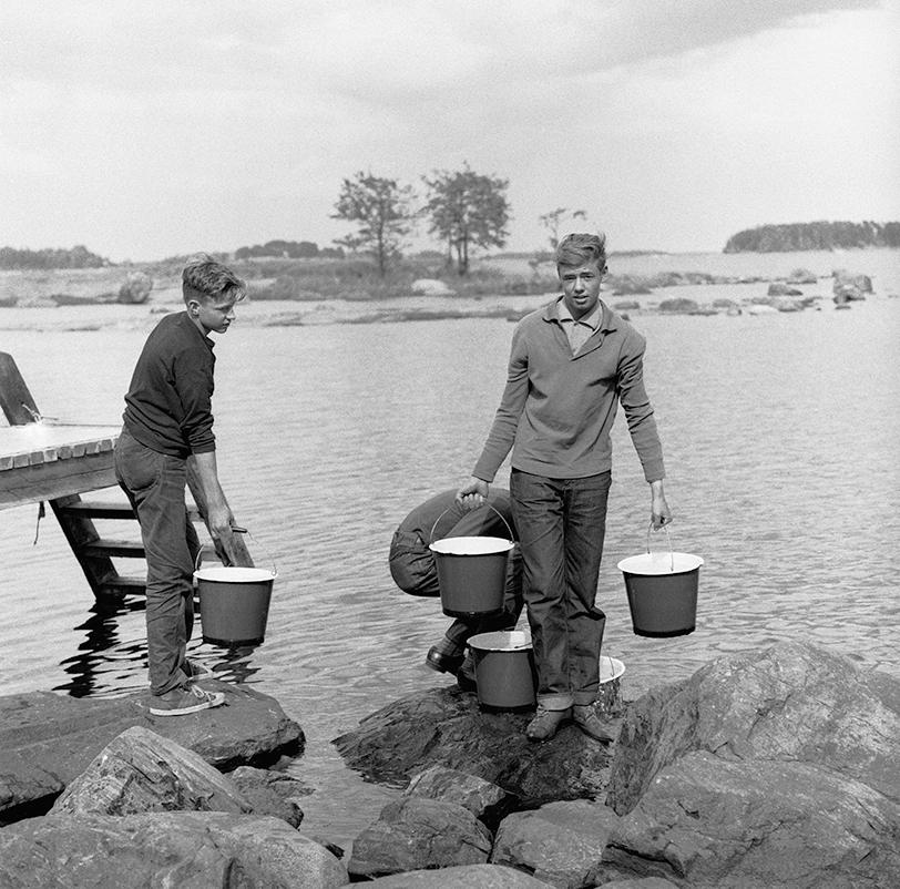 Rippikoululaisia kantamassa vettä saunaan Helsingin Kivisaaressa kesällä 1964. Tänä vuonna rippikoulun käy pääkaupunkiseudulla noin 7000 nuorta.