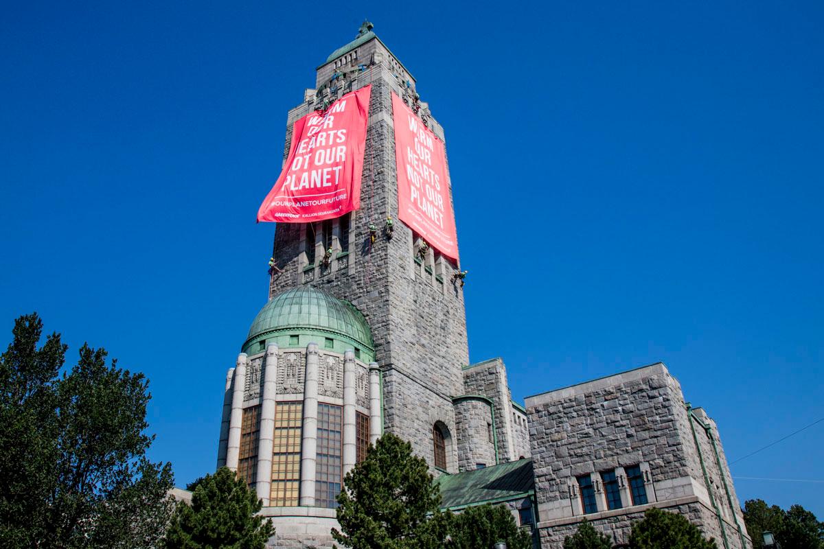 Greenpeace ja Kallion seurakunta ripustivat Kallion kirkon torniin kaksi banderollia.