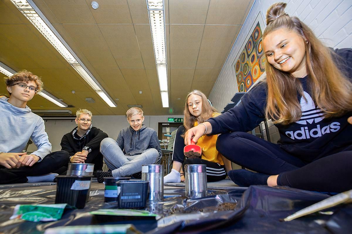 Mathias Castren (vas), Onni Turunen, Sami Paunonen, Noora Siidorov ja isonen Saara Koskinen istuttavat siemeniä Holmassa.