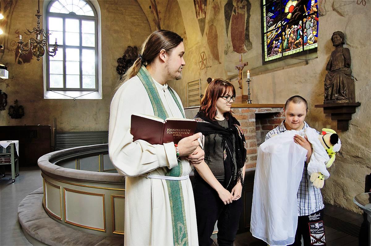 Pastori Tapio Leinonen, työpari Ella Luoma ja riparilainen Roni Simonen viettävät kastejuhlaa erityisriparin kirkkohetkessä.