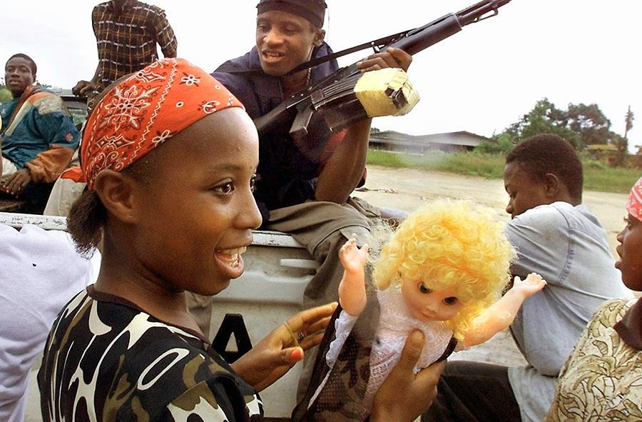 Tyttösotilas ja nukke Monrovian liepeillä Liberiassa vuonna 2003. Kuva: Lehtikuva / AFP / Georges Gobet