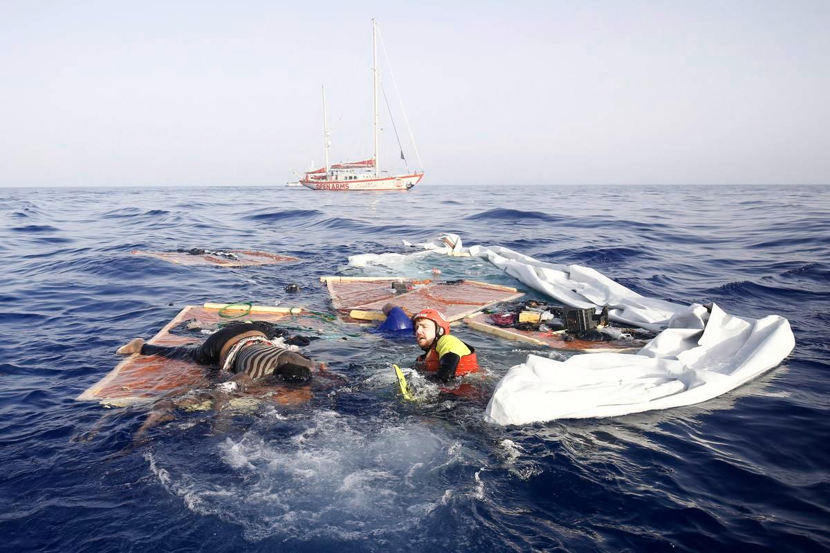 Espanjalaisen Open Arms -kansalaisjärjestön jäsen pelastaa naista uponneesta veneestä Välimerellä 85 mailin päässä Libyan rannikolta. Vieressä kelluu hukkunut matkustaja.