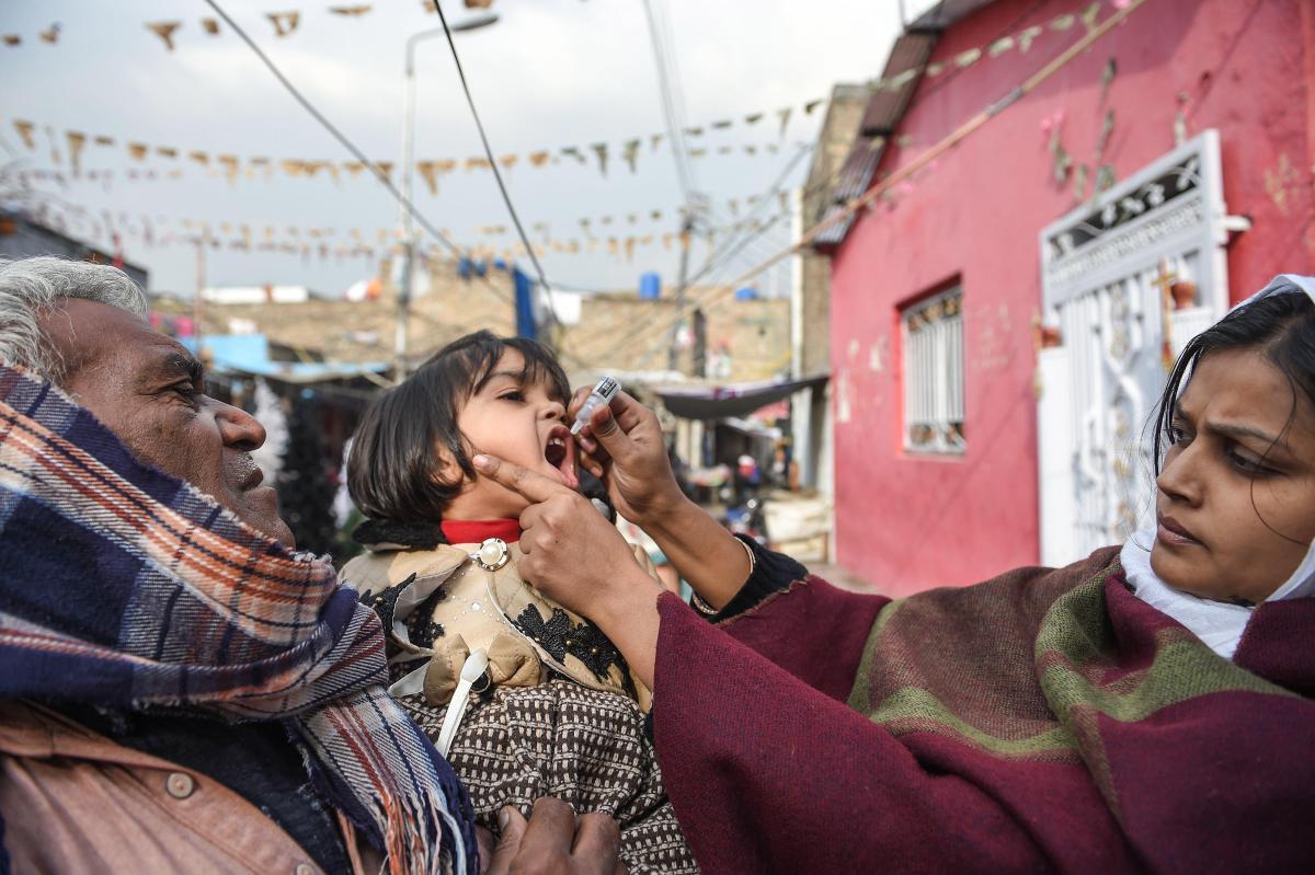 Pakistanilainen ja kristitty terveydenhuollon työntekijä antaa polio-rokotteen lapselle rokotuskampanjan aikana Islamabadin kristillisessä siirtokunnassa 12.12.2018. Kuva: Farooq Naeem / AFP – Lehtikuva