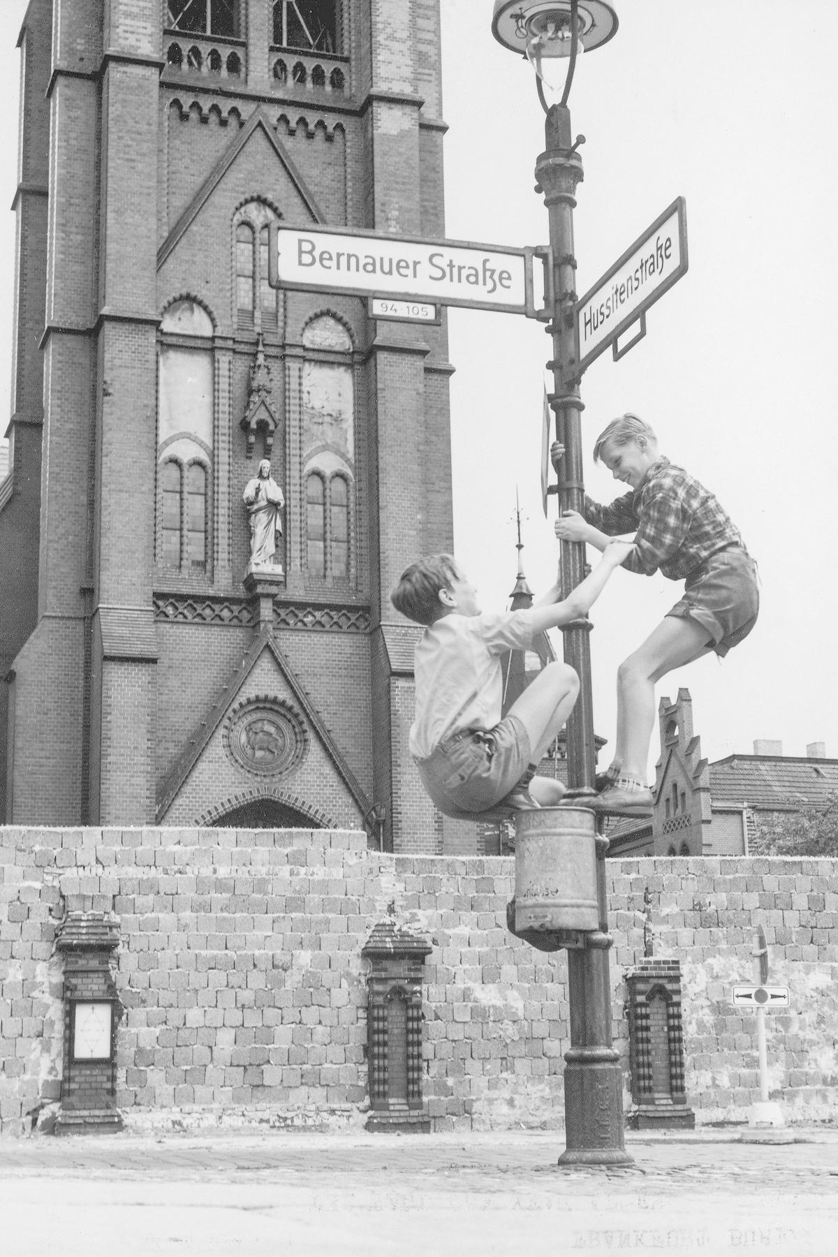 Kaksi länsiberliiniläistä poikaa leikkii Berliinin muurin edustalla. Taustalla näkyy Itä-Berliinin puolella oleva kirkko. Kuva: Lehtikuva