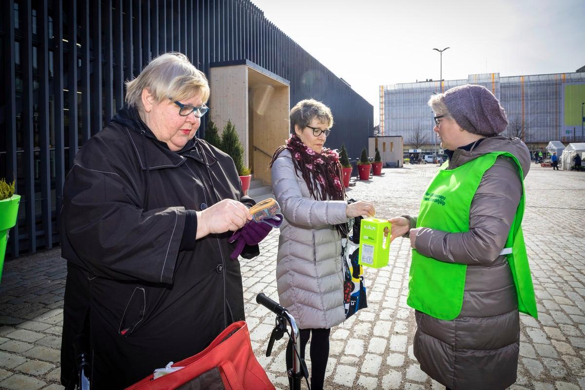 Mirja Salönen ja Mari Sjöholm laittoivat Hakaniemen torilla lahjoituksensa pappi Mari Mattssonin keräyslippaaseen.