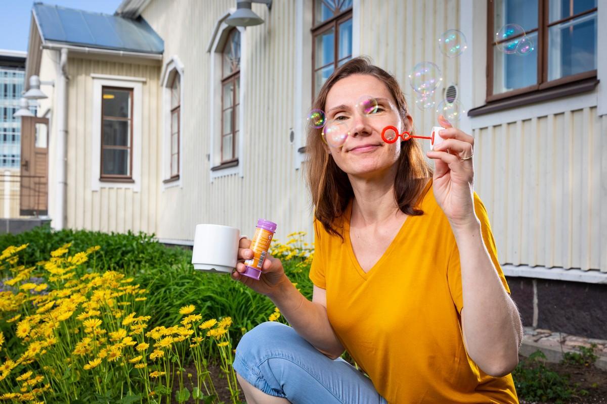 Perheiden kesäkahvilassa Perkkaan kappelilla voi puuhailla monenlaista sekä sisätiloissa että ulkona, esimerkiksi puhaltaa saippuakuplia. Leppävaaran seurakunnan lastenohjaaja Marika Laakkonen näyttää mallia.