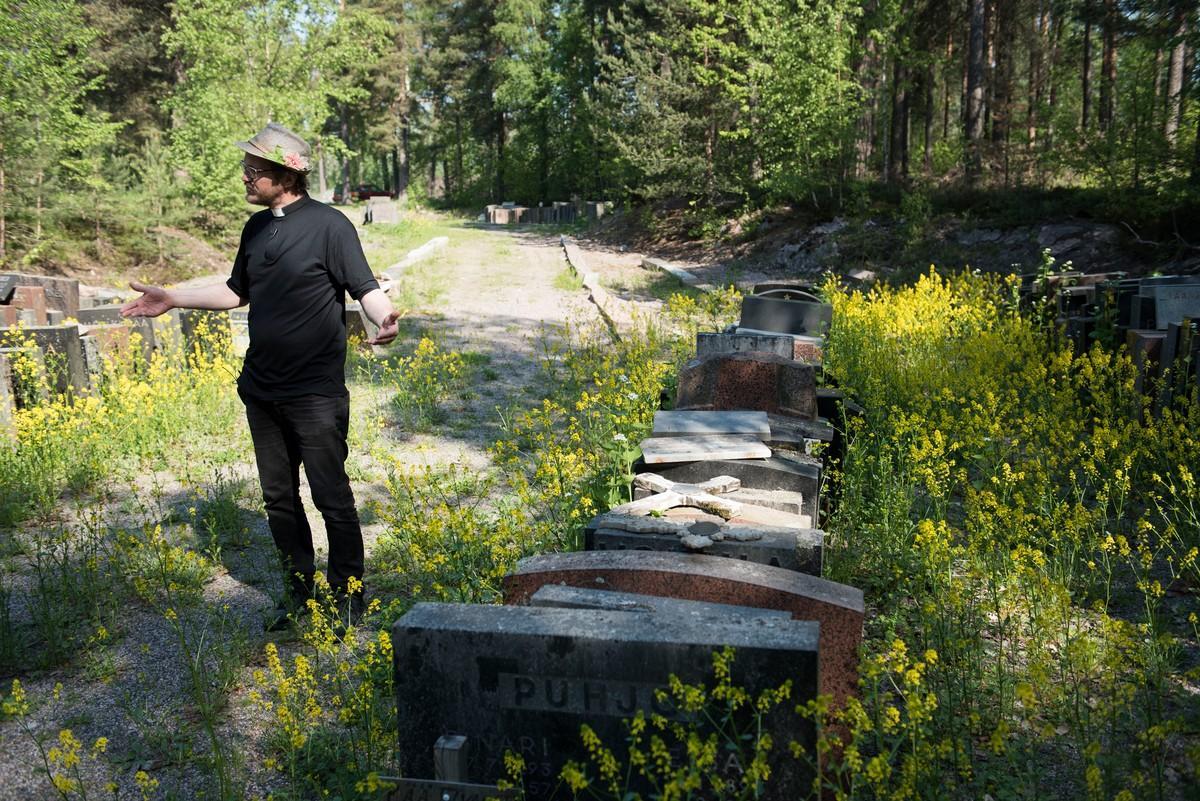 Pappi Kai Sadinmaa esittelee poistettujen hautakivien varastoaluetta, joka on piilossa tavallisilta kävijöiltä.