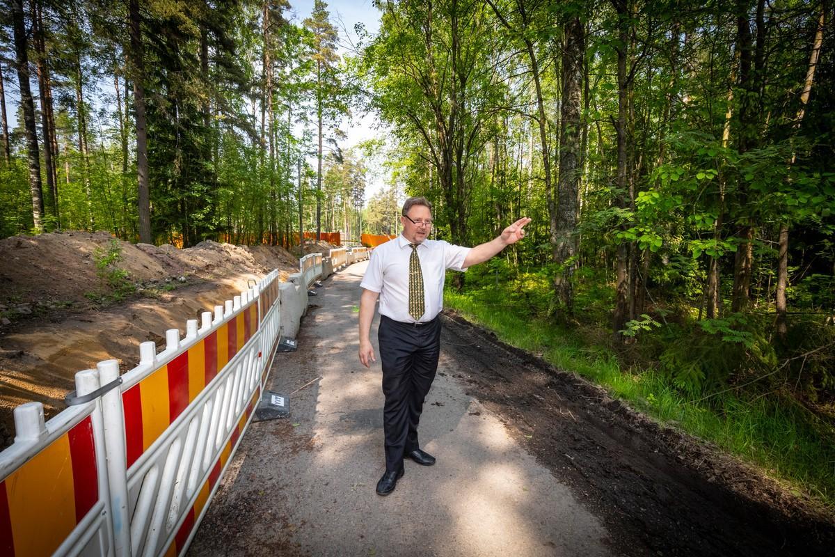 Espoon seurakuntayhtymän kiinteistöjohtaja Petteri Leinonen osoittaa metsikköä, joka on tarkoitus säilyttää. Toiselle puolelle pyörätietä tulee asuntoja.