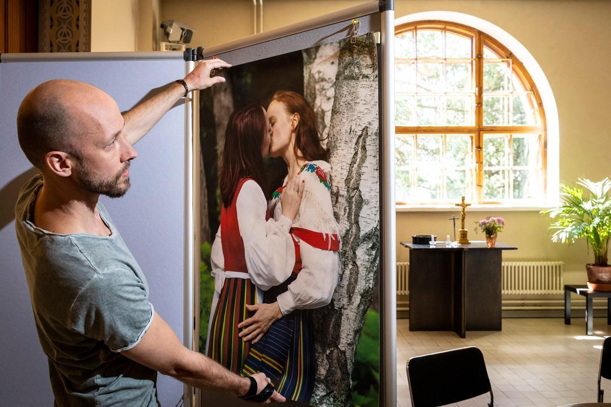 Taakasta voimavaraksi -hankkeen koordinaattori Peik Ingman ripusti valokuvia esille maanantaina Kallion kirkon seurakuntasalissa. Kansallispuvuissaan suuteleva kaksikko on näyttelyn valoisinta antia.