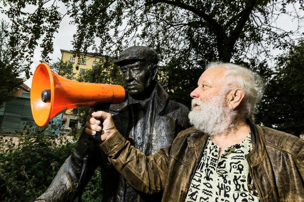 Ääni kodittomalle. Ilkka Taipale ojentaa megafonin asunnottomien auttajan Arvo Kustaa Parkkilan näköispatsaalle. Patsas sijaitsee Lapinlahden puistikossa Helsingissä. Kuva: Jukka Granström