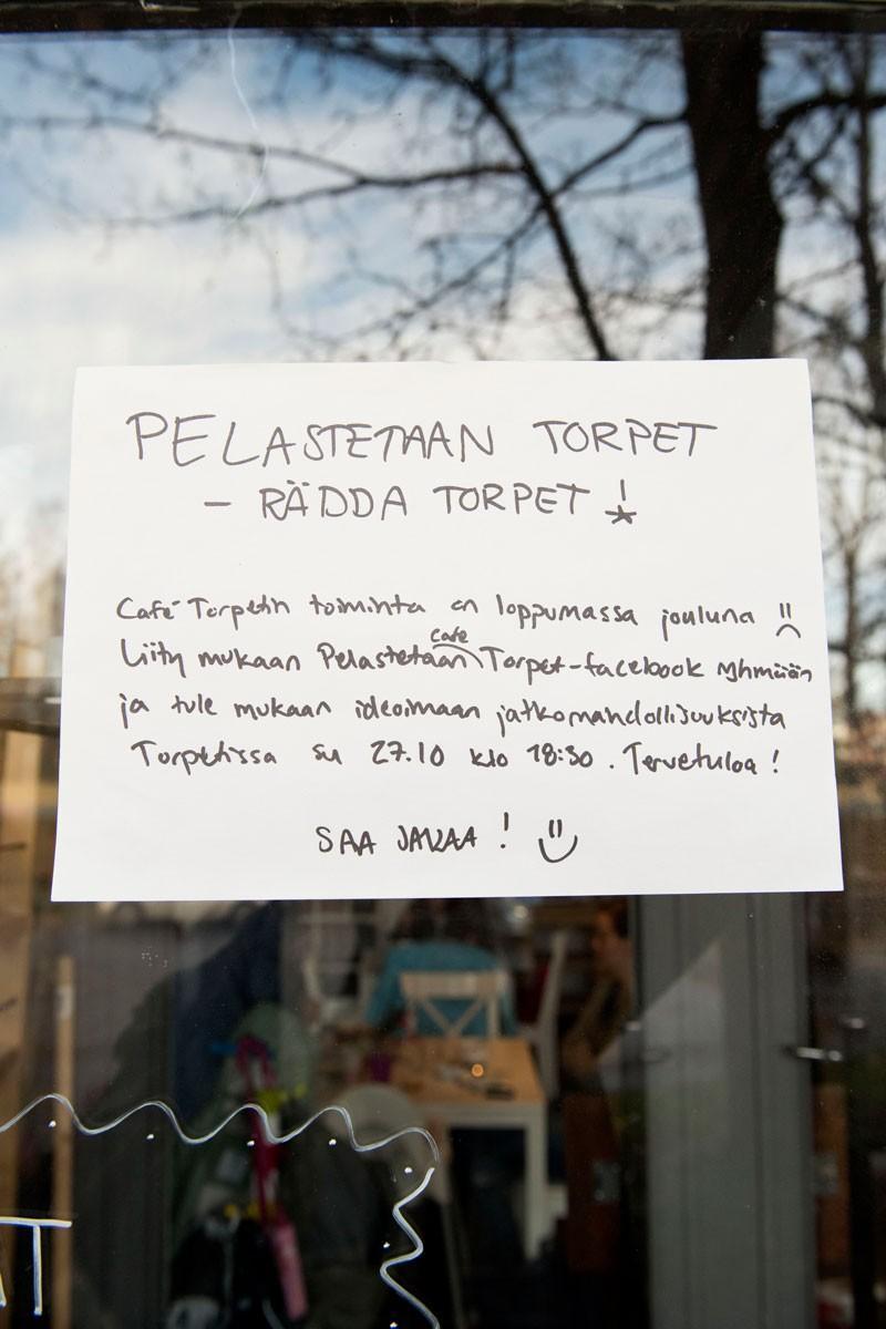 Kahvilan ikkunassa mainostetaan Pelastetaan Café Torpet -Facebook-ryhmää.