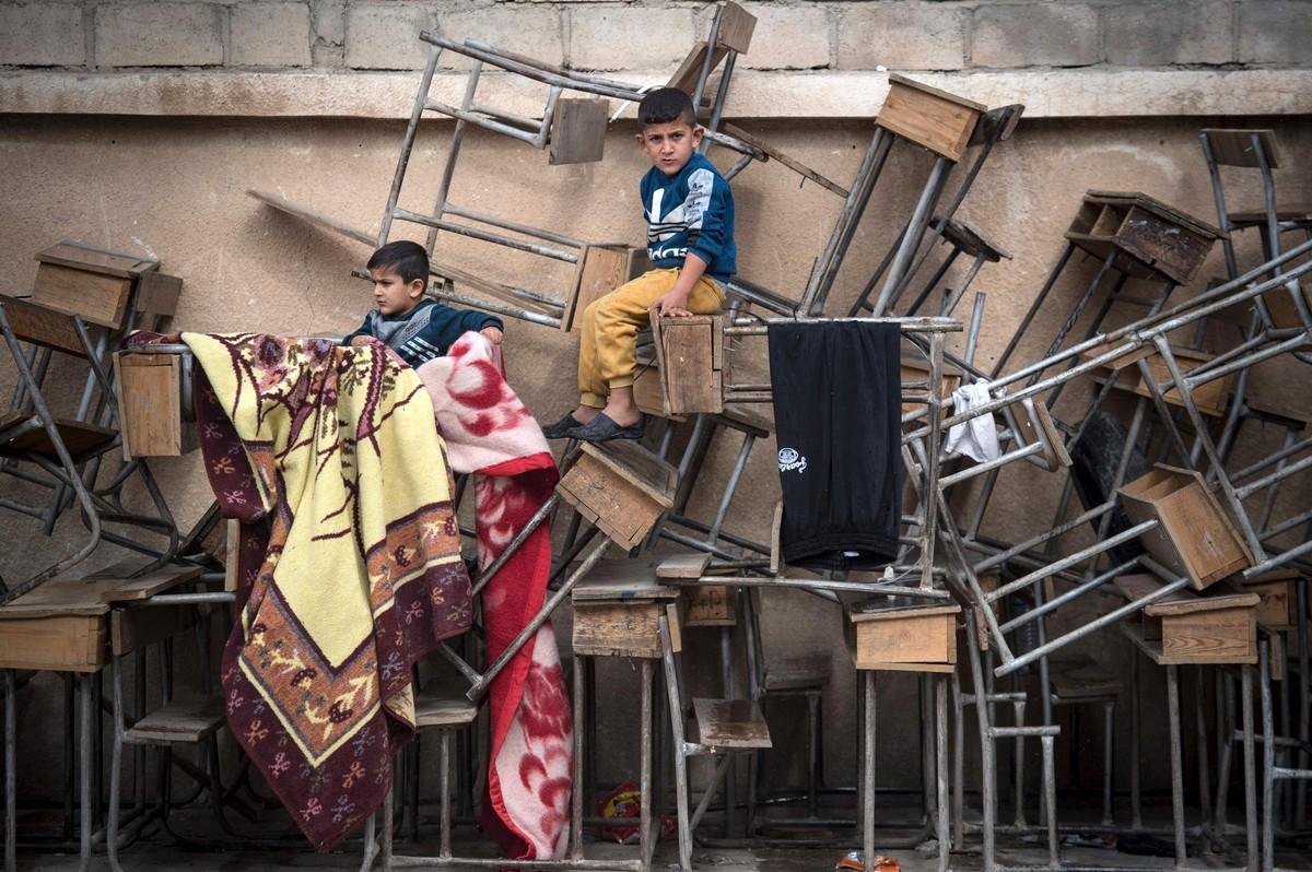 Pakolaislapset kiipeilivät pulpettien päällä koulussa, josta tehtiin majoituskeskus Hasakassa Koillis-Syyriassa.