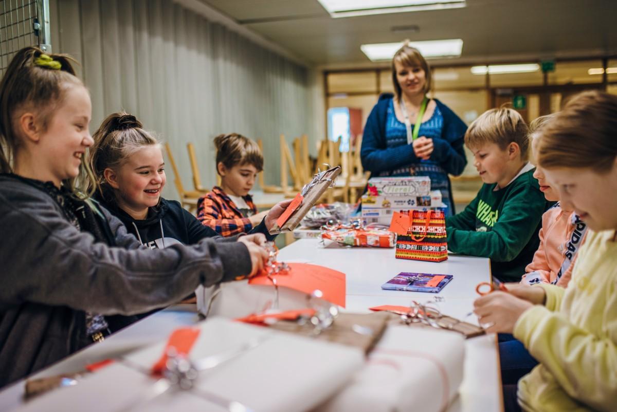 Opettaja Hanna Haapanen seuraa, kun Milaya, Jenna, Alvar, Aaro, Jemina ja Venla viimeistelevät paketteja.