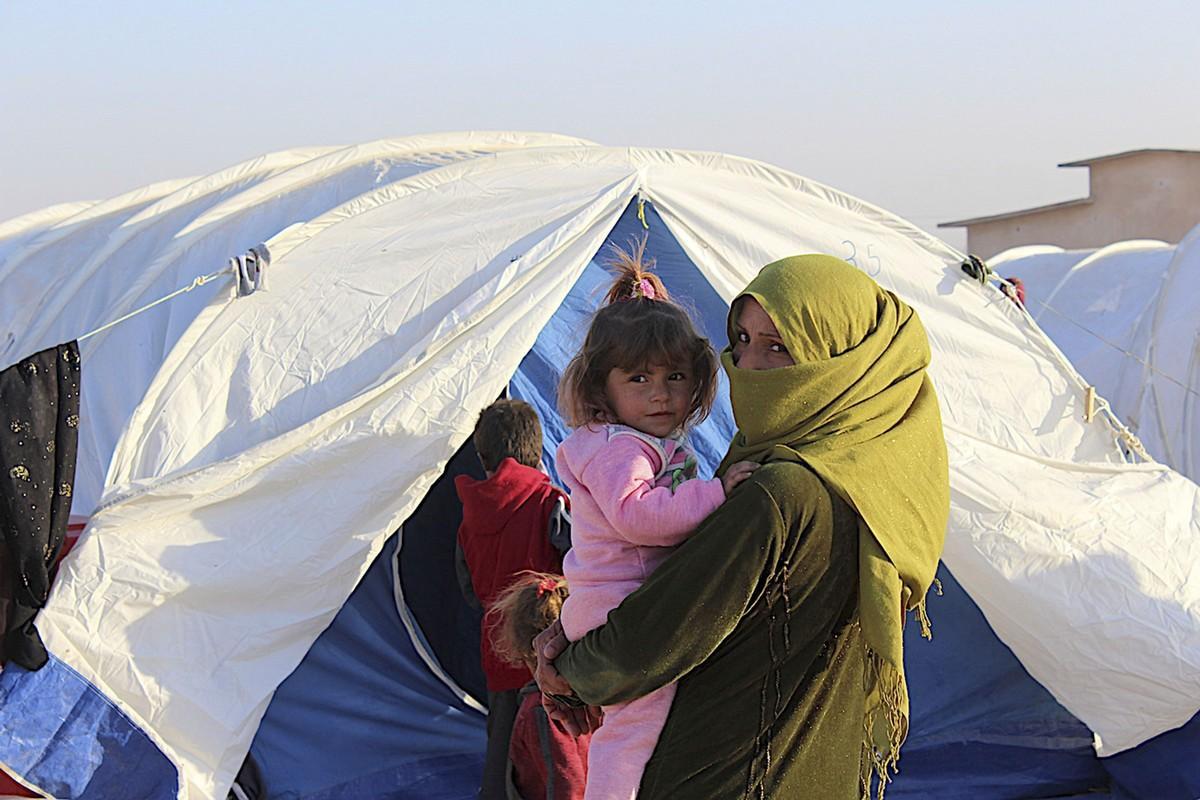 Äiti pitelee lasta sylissään pakolaisleirillä kymmenen kilometrin päässä Hasakan kaupungista.