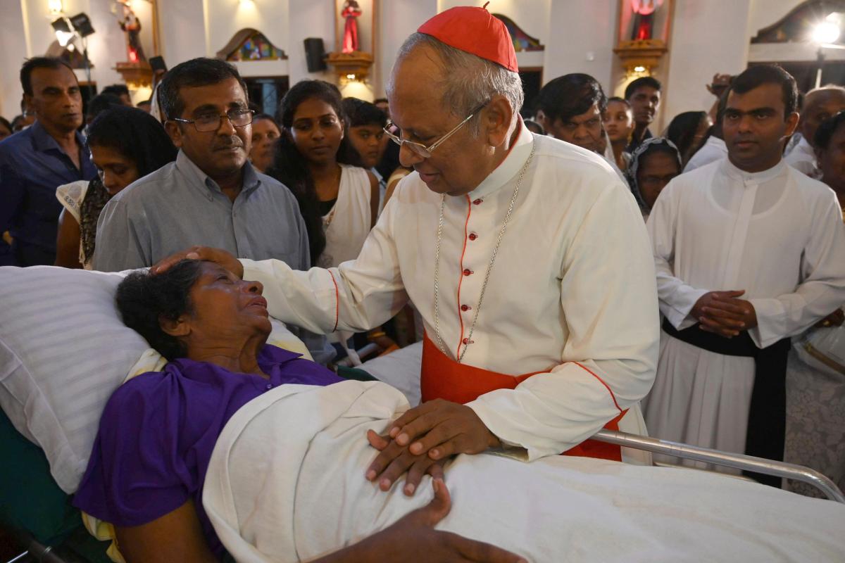 Sri Lankan pääkaupungin Colombon arkkipiispa Malcolm Ranjith siunasi pääsiäisiskusta selvinneen ja vaikeasti haavoittuneen naisen joulupäivän messussa. Kuva: Lakruwan Wanniarachchi, Lehtikuva / AFP 