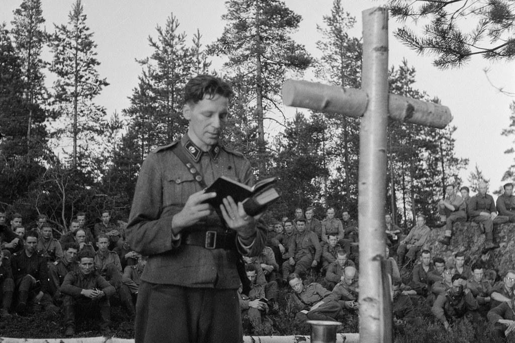 Sotilaspastori Salminen suorittaa jumalanpalvelusta jatkosodan aikana Sintolan kylässä Karjalankannaksella. Kuva: SA-kuva