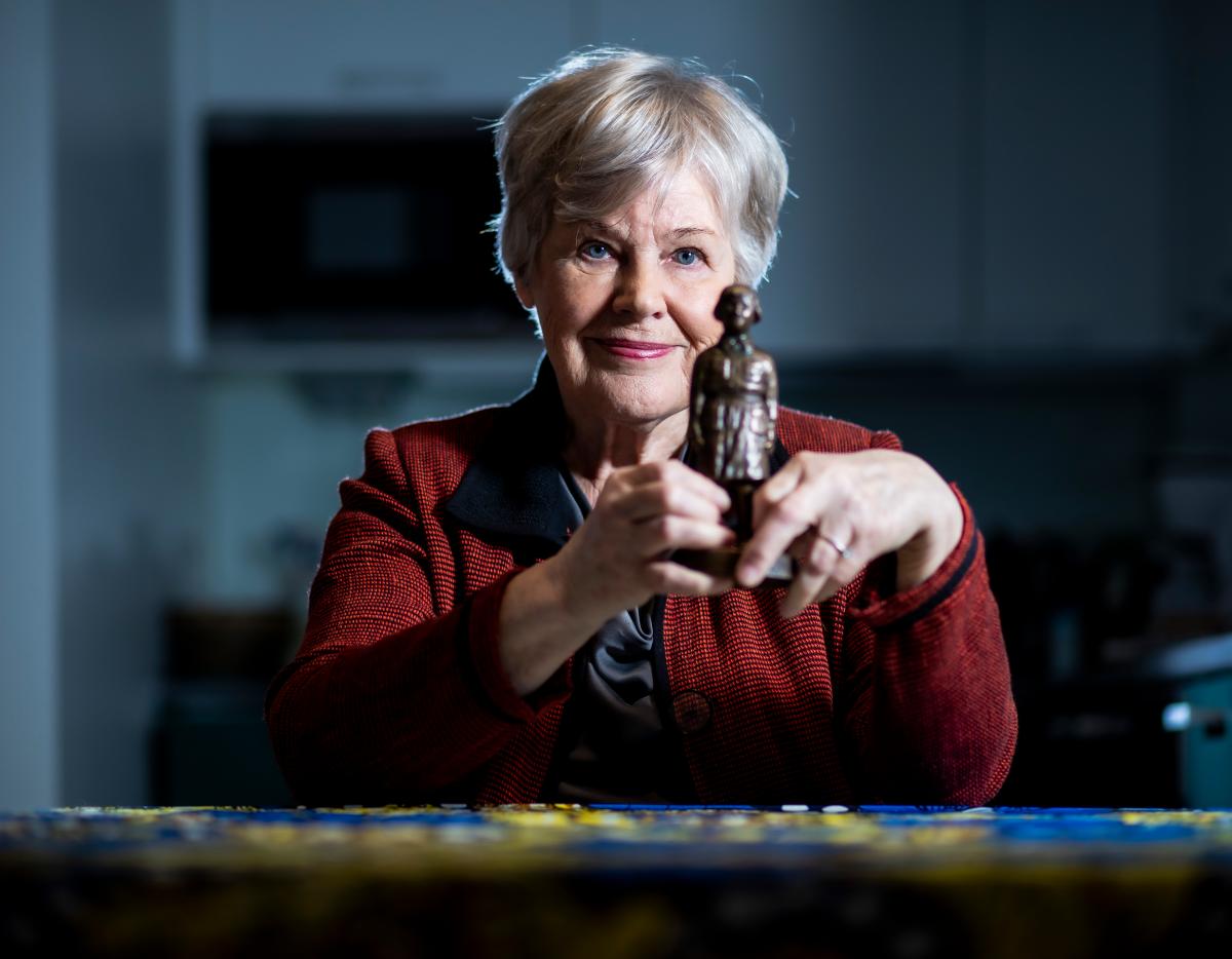 Elisabeth Rehn pitelee kädessään pikkulottapatsasta, jonka hän on saanut työstään lottien nostamisesta uudelleen arvoonsa.