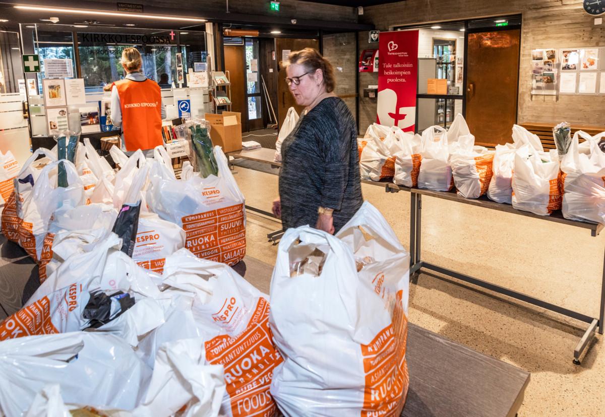 Diakoniatyöntekijä Eija Siivonen ja vapaaehtoinen Tarja Toivanen jakavat ruokakasseja kirkon aulassa.