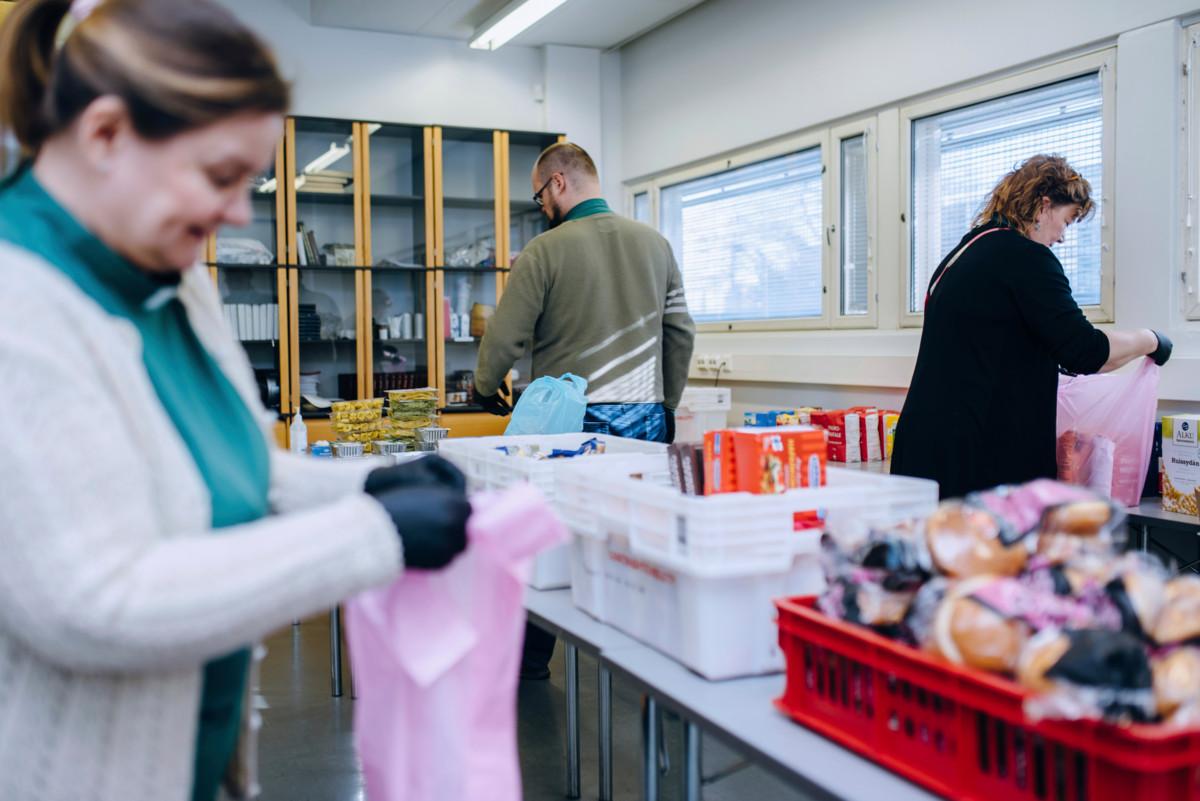 Tikkurilan seurakunnan diakoniatyöntekijät Kaisa Aalto, Mikko Pihlgren ja Hanna Raunu pakkaavat hätäruoka-apua kasseihin.
