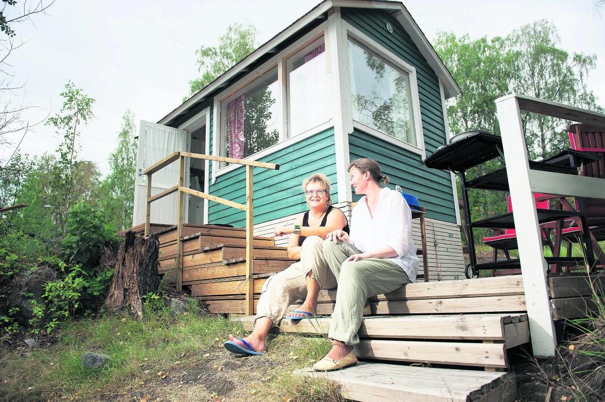 Kesämajan rappusilla. Anu Suoranta (vas.) ja Kirsi Mäki ovat osakkaina Kivinokan yhteismökissä, jossa on mukana seitsemän aikuista, pari lasta ja koira. Tärkeä sääntö on, että kaikki osakkaat ovat aina tervetulleita.