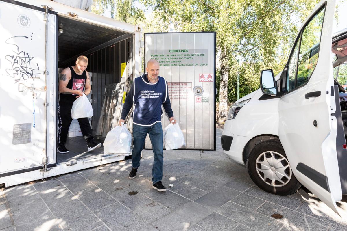 Kesätyöntekijä Jouka Mäenpää (vas.) auttaa Samu Konttista lastaamaan päivän ruoka-apukassit F-Securen autoon Matteuksenkirkon pihalla sijaitsevasta kylmäkontista.