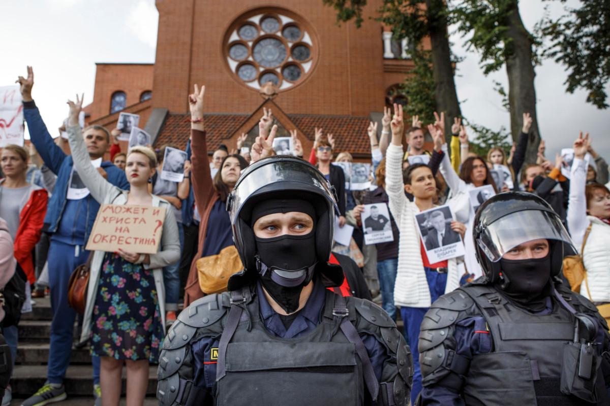 Mellakkapoliisit vartioivat katolisen kirkon eteen kokoontuneita mielenosoittajia Minskissä 27. elokuuta. Kuva: Dasha Sapranetskaya / AP / Lehtikuva