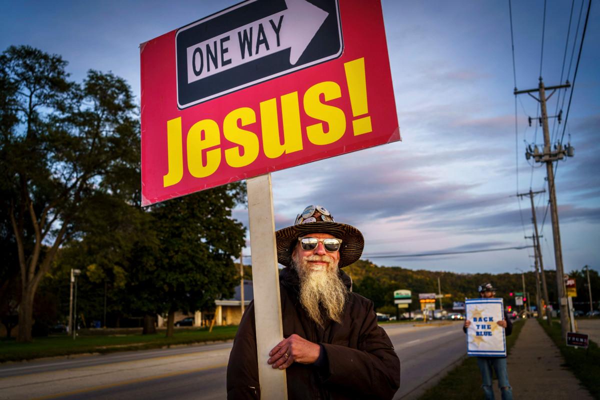 Donald Trumpin kannattaja heiluttaa Jeesus-kylttiään Wisconsinissa, yhdessä tulevien presidentinvaalien ratkaisun kannalta kriitttisistä osavaltioista. Taustalla näkyy demokraattien ehdokkaan Joe Bidenin kannattaja. Yhdysvallat on nyt ideologisesti hyvin kahtiajakautunut yhteiskunta. Uskonnolla on kahtiajaossa merkittävä rooli.