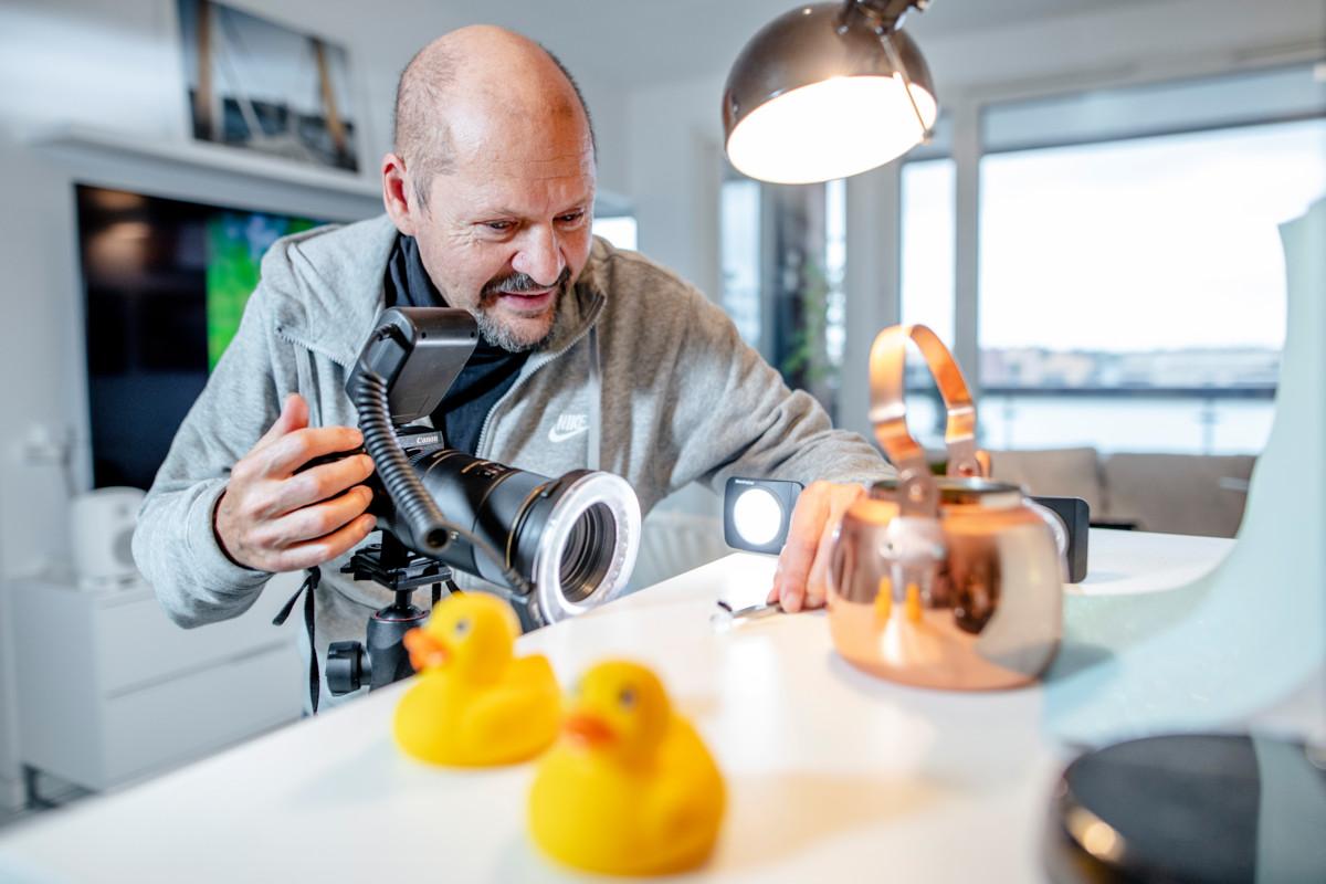 Jussi Mankki kuvaamassa kärpästä pöydälle rakennetussa ministudiossa kuvaustaustanaan kuparipannu.  